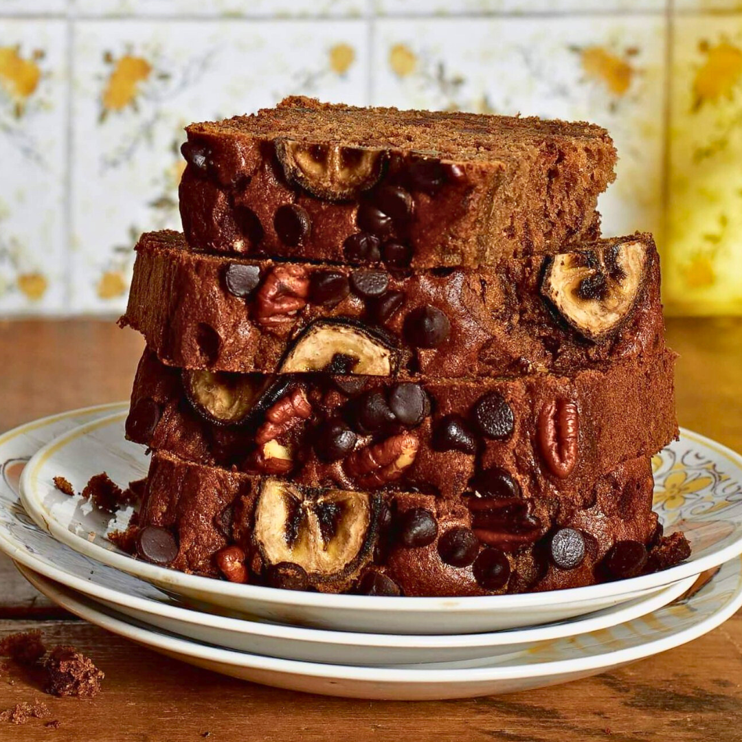 A stack of sliced of chocolate chip banana bread in front of yellow glasses and linoleum