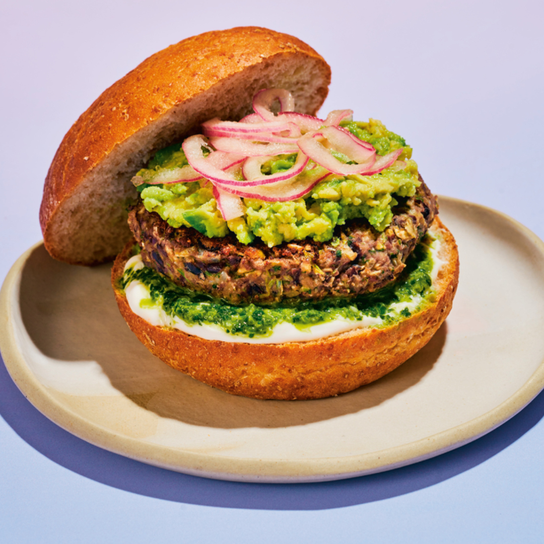 Black bean burger with smashed avocado, pickled red onion and sauce served on a whole wheat bun