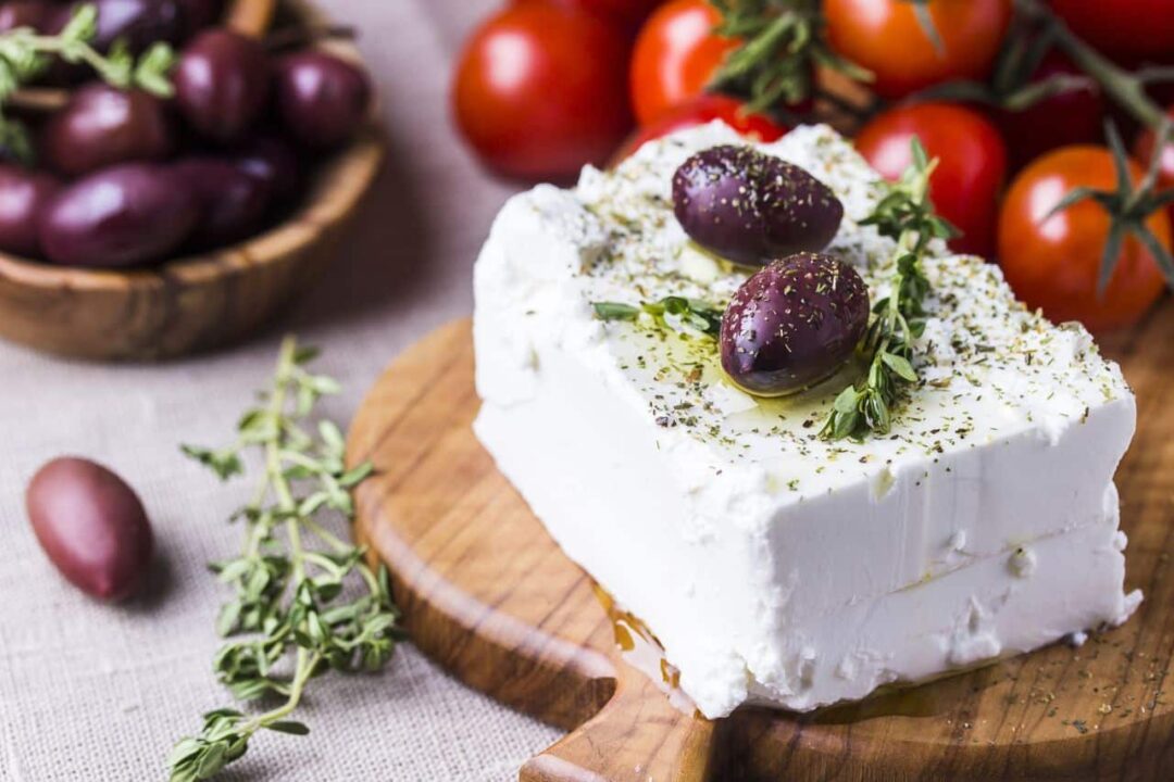 beautiful piece of Greek feta with kalamata olives on top drizzled with oil