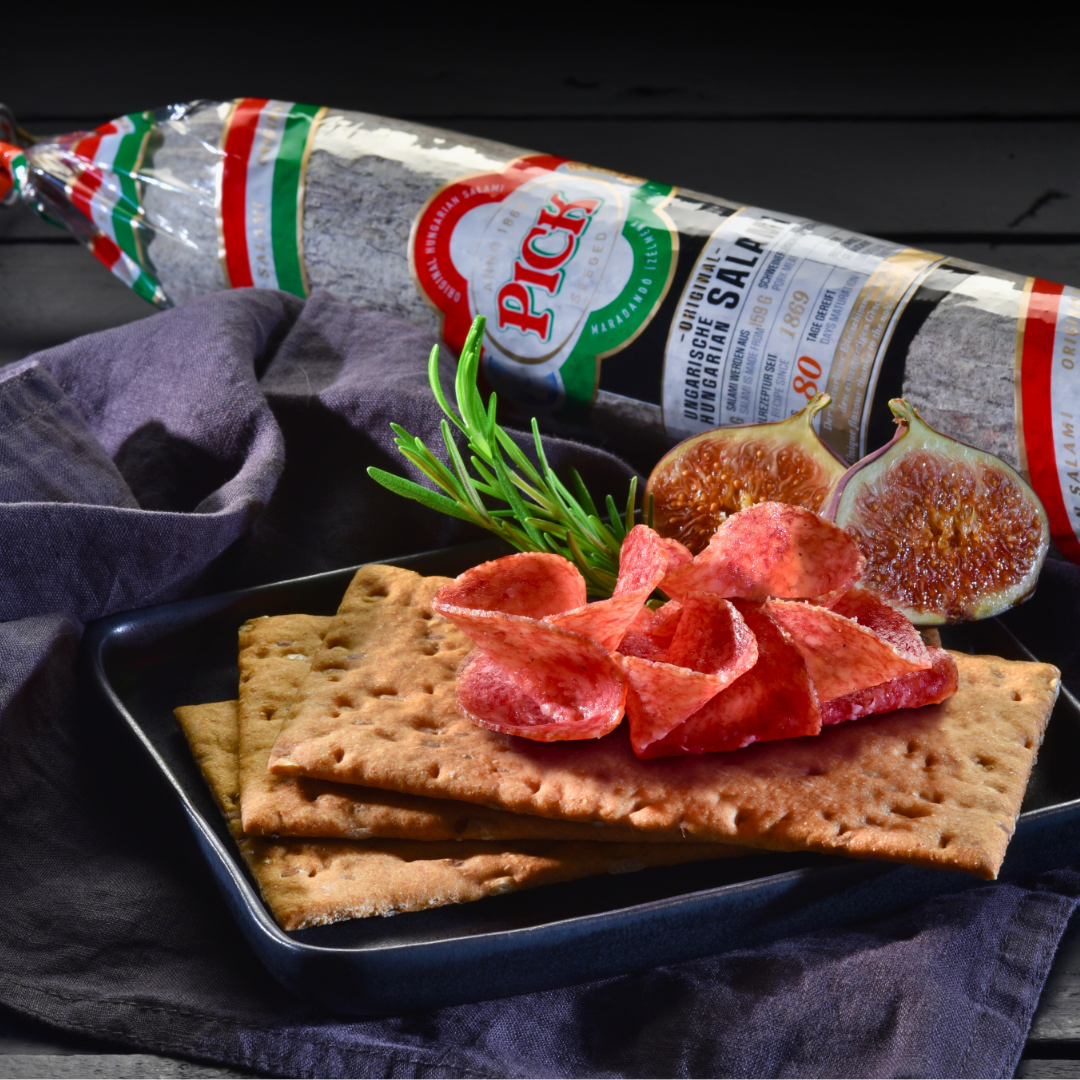 Hungarian Pick WinterSalami on a table with crackers and pieces of salami and figs