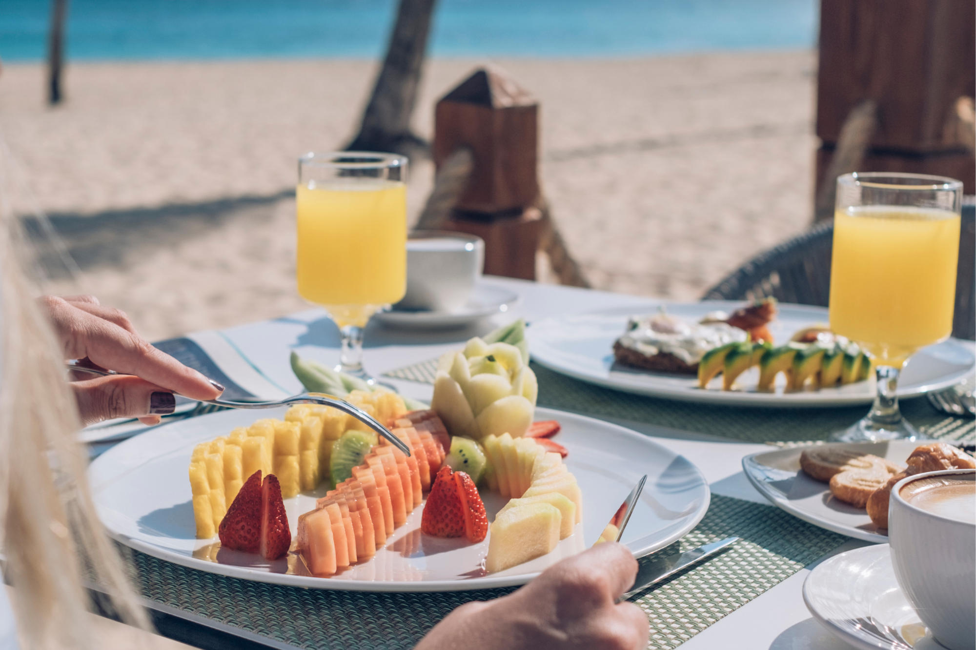 Beautiful beachside breakfast with perfectly cut tropical fruit and a mimosa