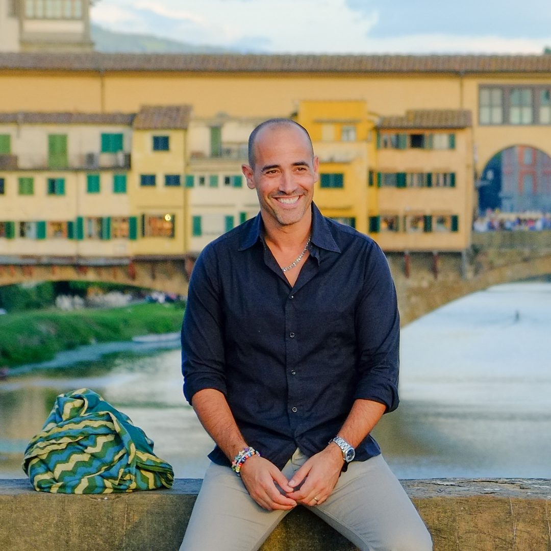 Canadian Chef David Rocco sitting casually on a bridge in Florence