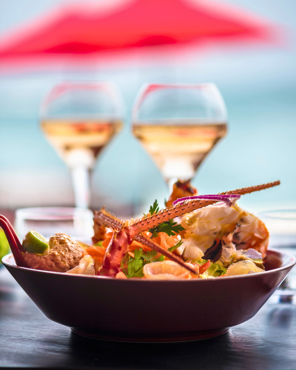 Restaurant La Toubana, has a dish of grilled seafood in front of two glasses of rose – Guadeloupe Islands Tourism Board