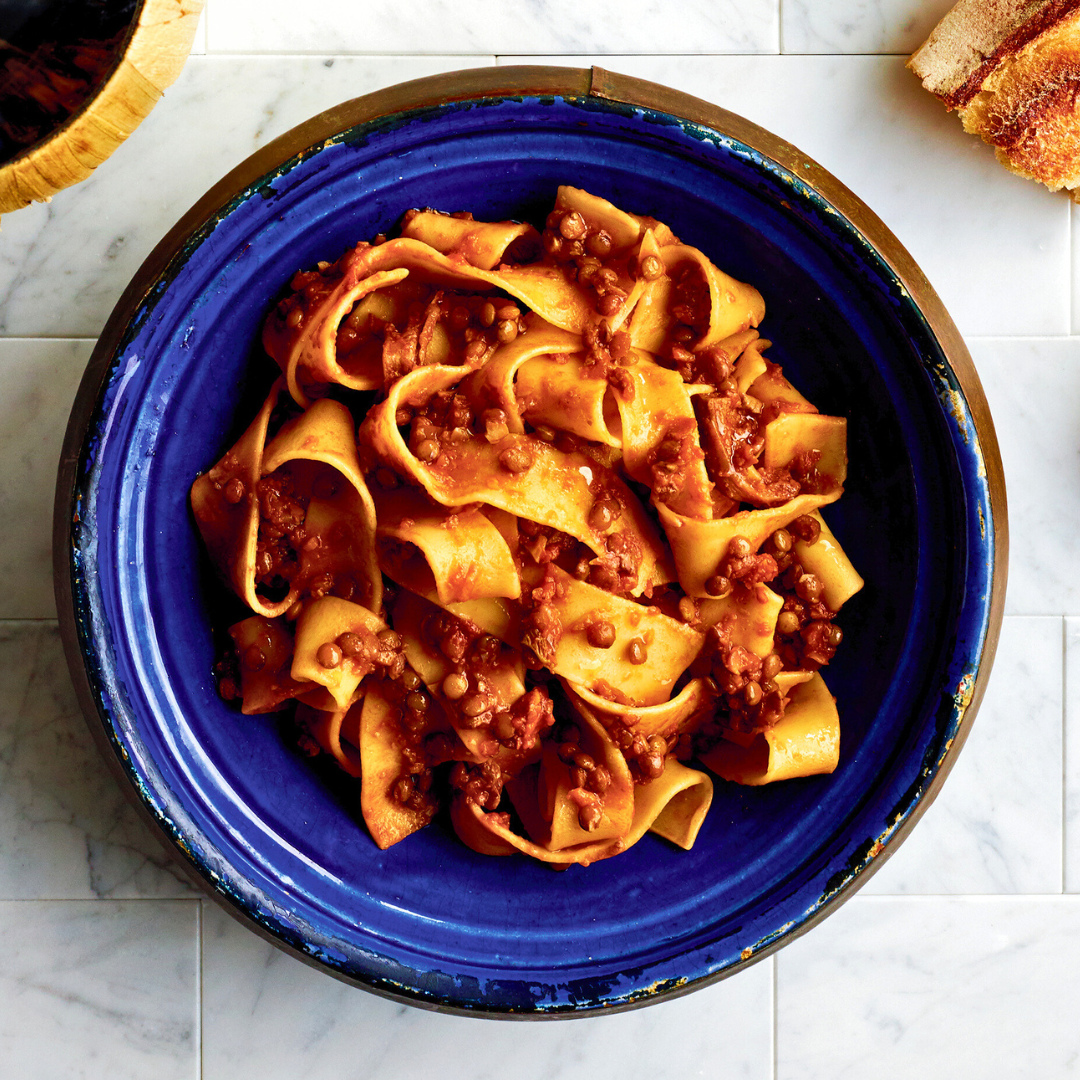 Blue bowl filled with bolognese with lentils and mushrooms.
