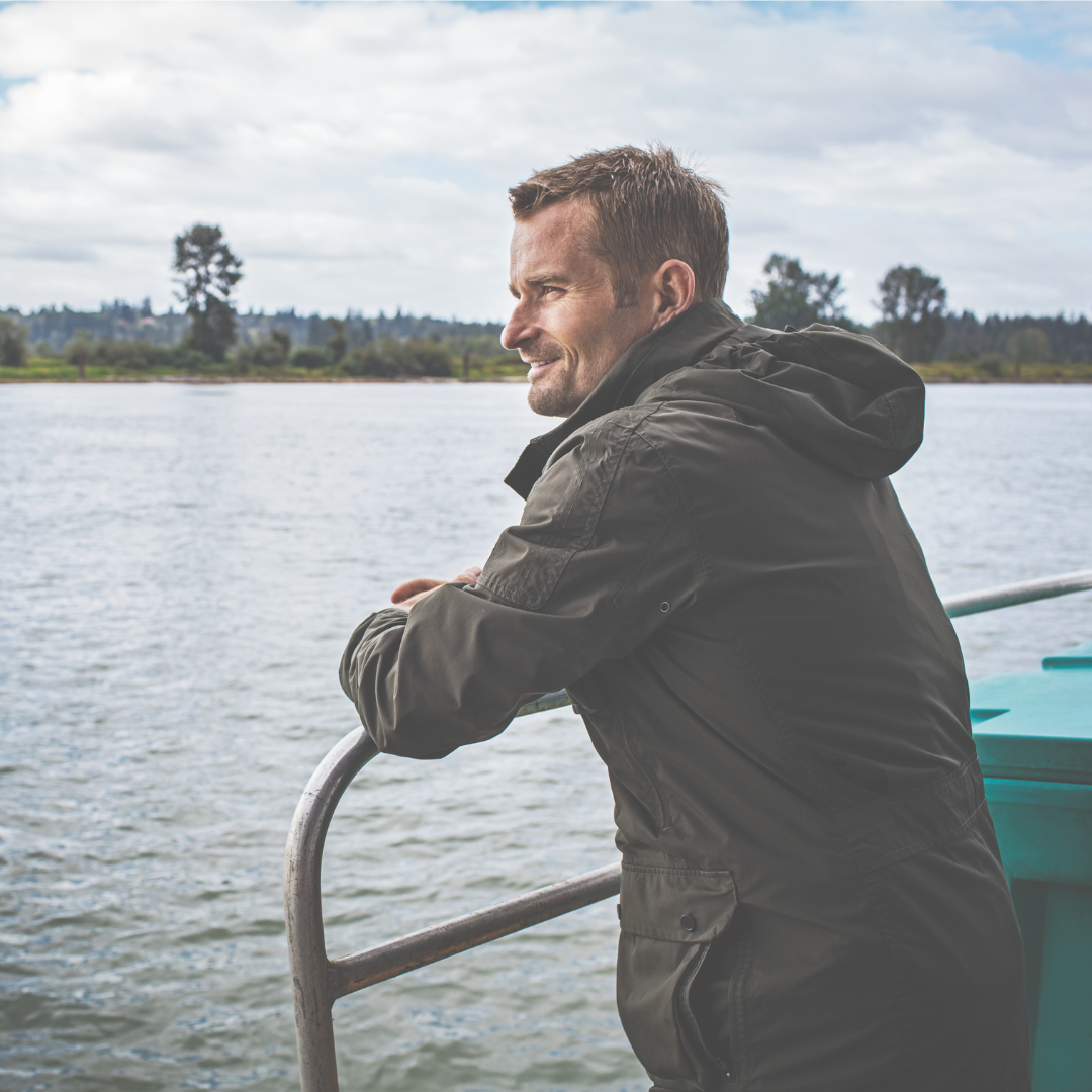 A man leaning against the railing looking out at the ocean.