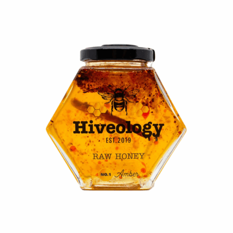 A hexagon-shaped jar filled with Chili Infused honey from Hiveology.