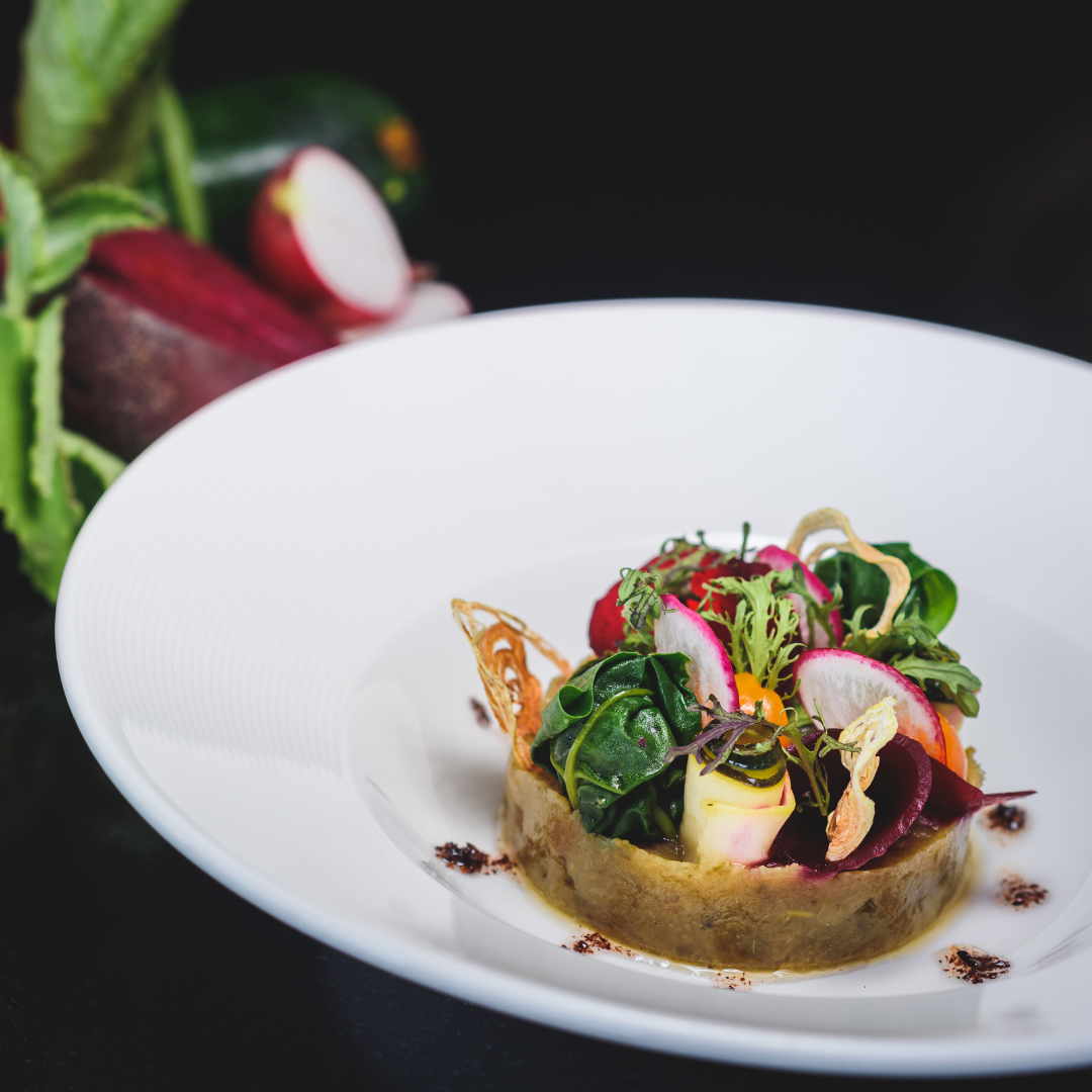 A white plate topped with an array of thinly sliced vegetables.