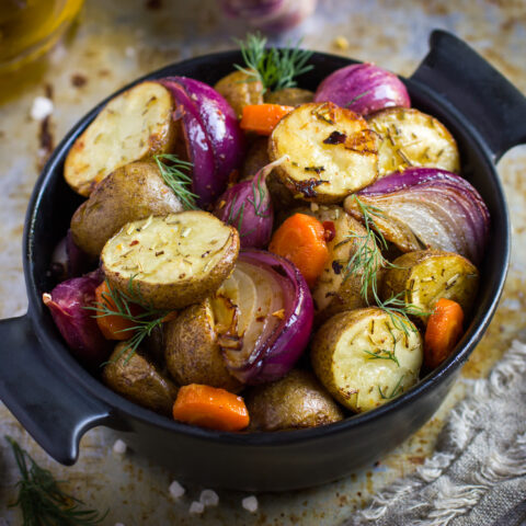 Oven roasted potatoes with onions, carrot and garlic in a cast iron pot