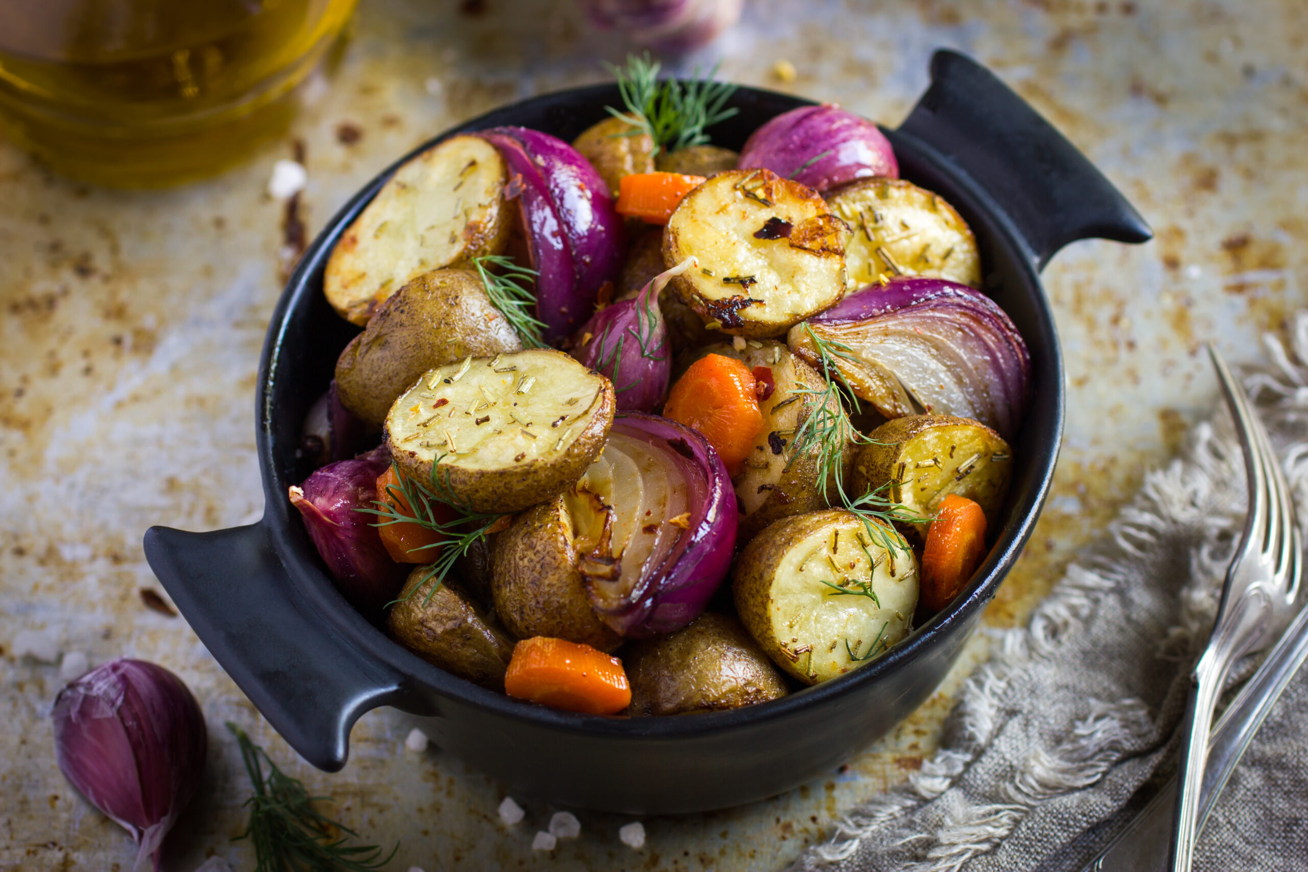 Oven roasted potatoes with onions, carrot and garlic in a cast iron pot
