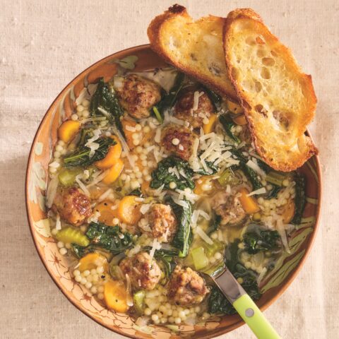 Bowl of Italian Wedding Soup with tender meatballs, fresh greens, and broth, served with a spoon