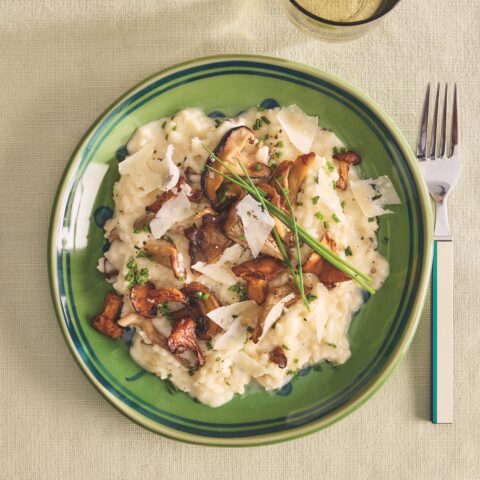 A green plate topped with risotto and mushrooms.