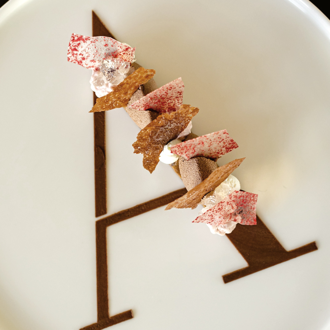A plate with a decorative letter A, topped with a dessert. 
