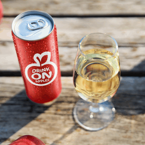 Ontario cider in a glass sitting beside a can