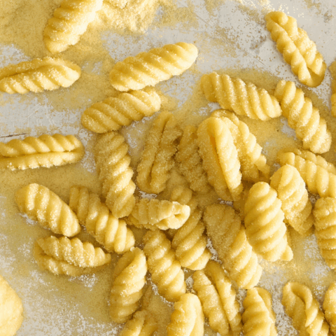 Uncooked cavatelli on a reflective surface.