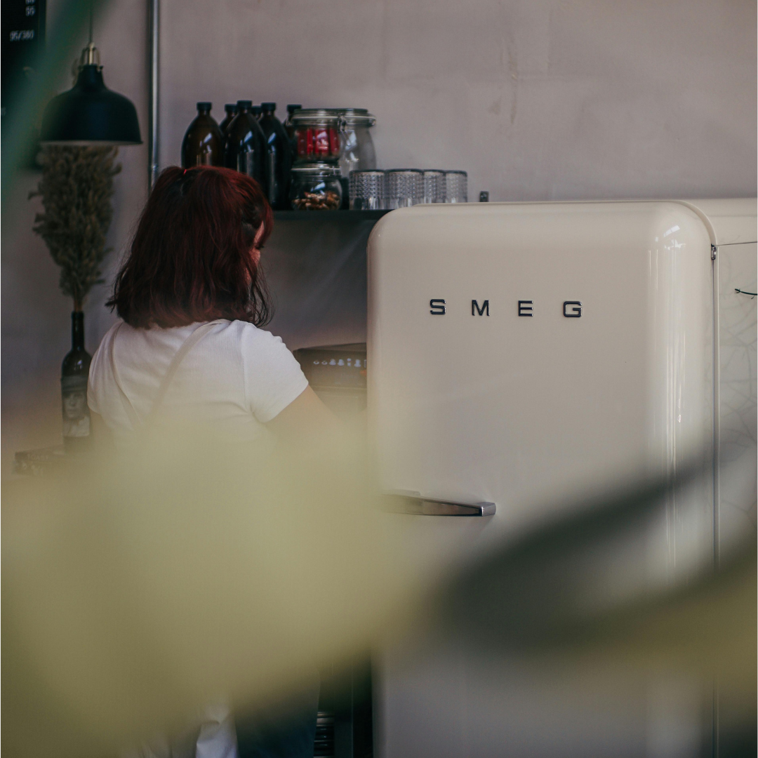 A person in a white t-shirt facing a white SMEG fridge.