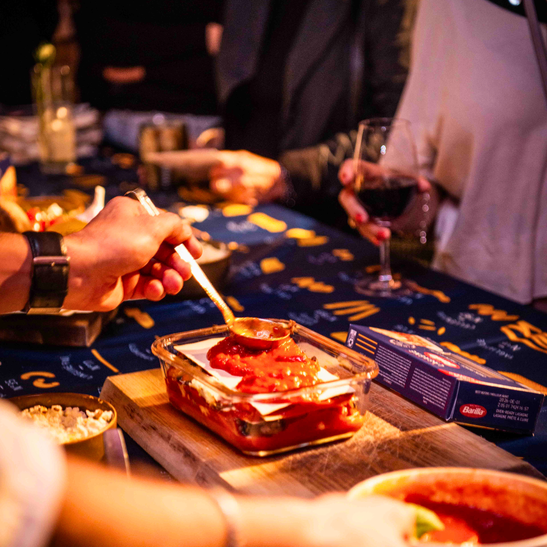 Pasta sauce being added with a ladle into a lasagna pan 