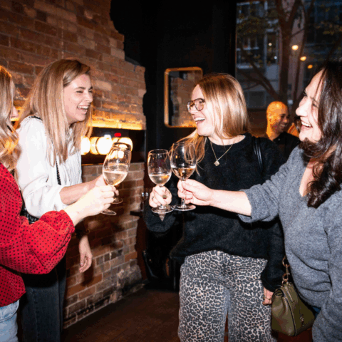 4 women at the ELLE Gourmet event saying cheers with glasses of white wine