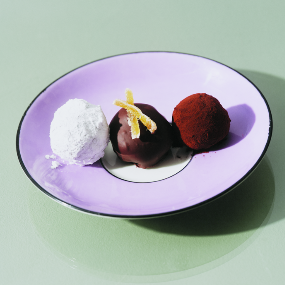 Three homemade chocolate ginger truffles on a vintage purple tea saucer. .