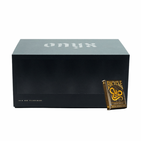 A black box with a deck of gold Bicycle cards in front of it.