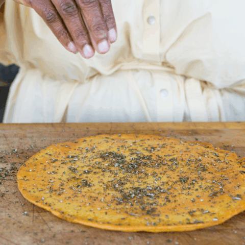 Chef Suzanne Barr is sprinkling sea salt on homemade socca, a flatbread made with chickpea flour