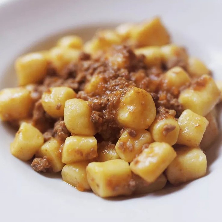 Close-up shot of a pasta dish topped with a meat sauce in a white dish.