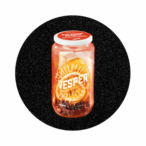 A glass jar with dried orange slices, dried hibiscus and dried bluberries inside.